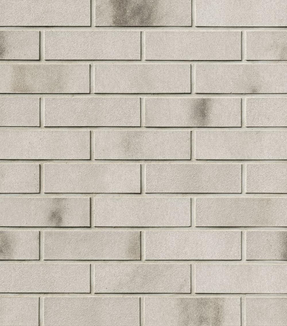 Helle Ziegelsteinwand mit dunklen Verfärbungen.