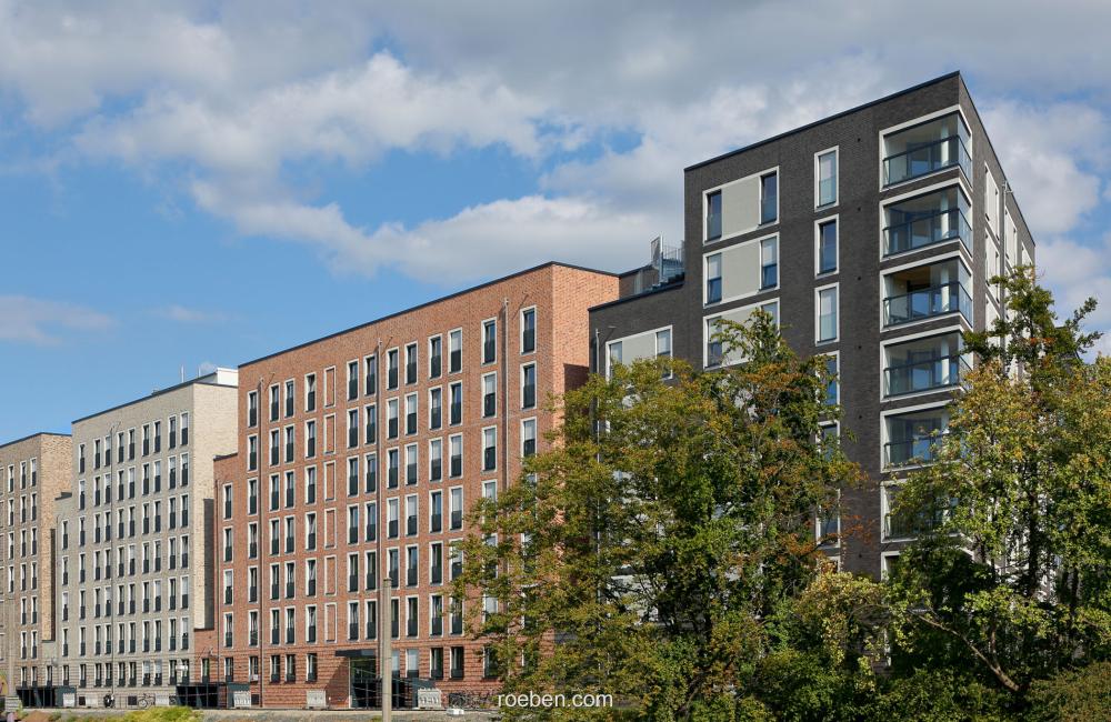 Moderne Wohngebäude unter blauem Himmel mit Bäumen im Vordergrund.