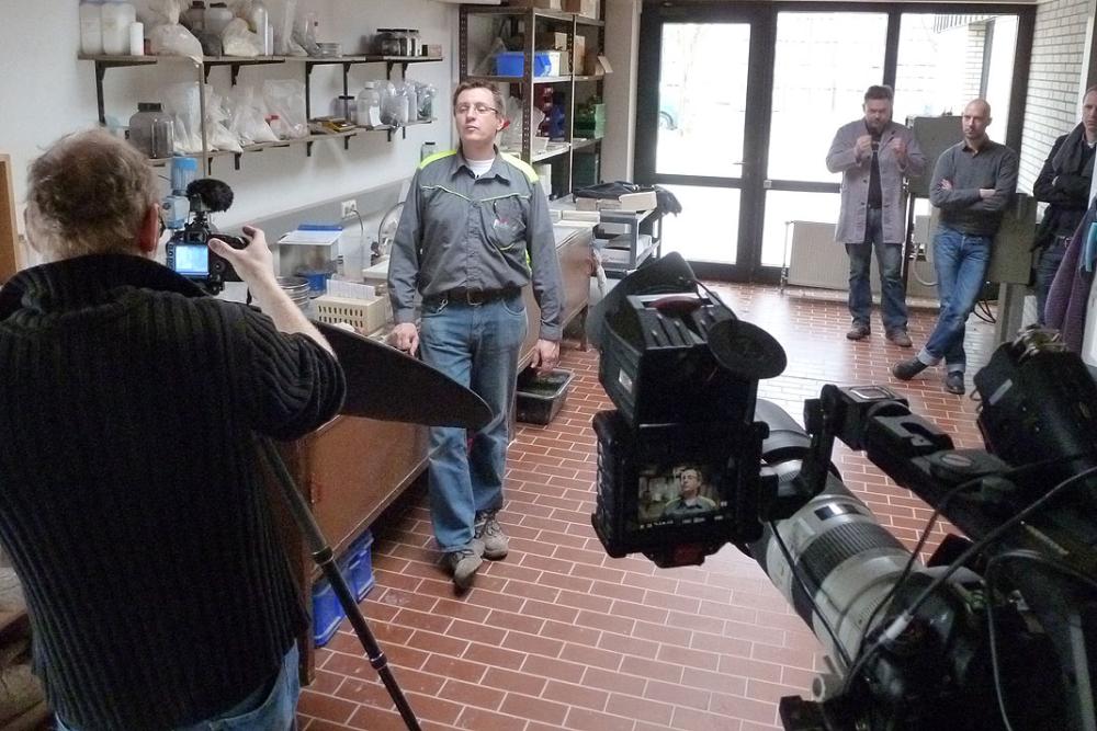 Filmcrew dreht in einem Labor; Kameras fokussiert auf eine Person in Freizeitkleidung.