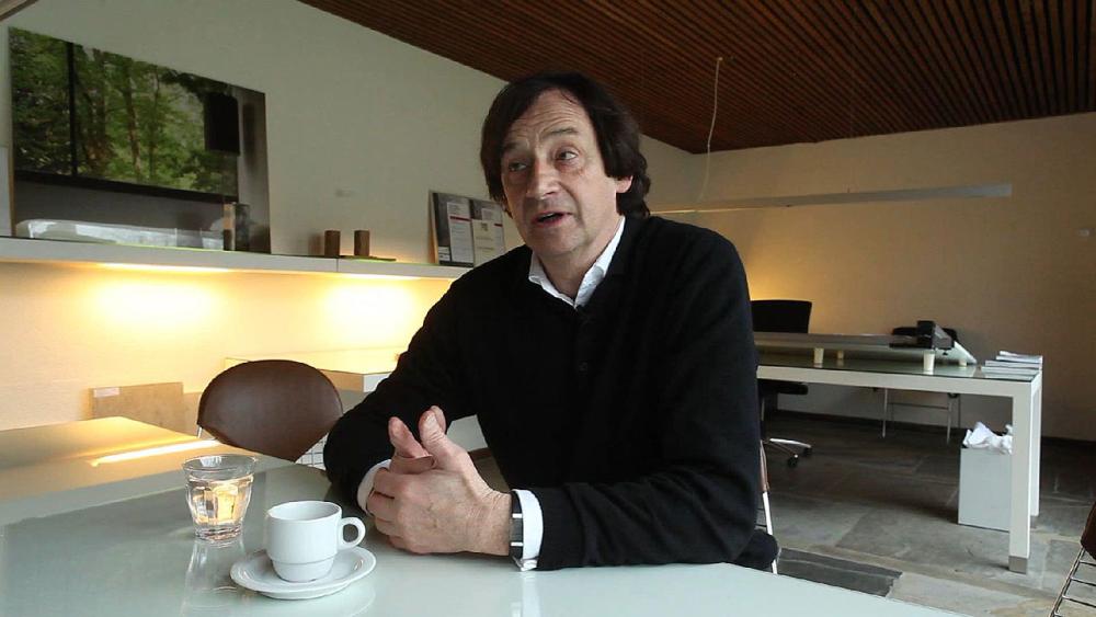 Mann sitzt an einem Tisch mit einer Tasse Kaffee in einem modernen Büro.