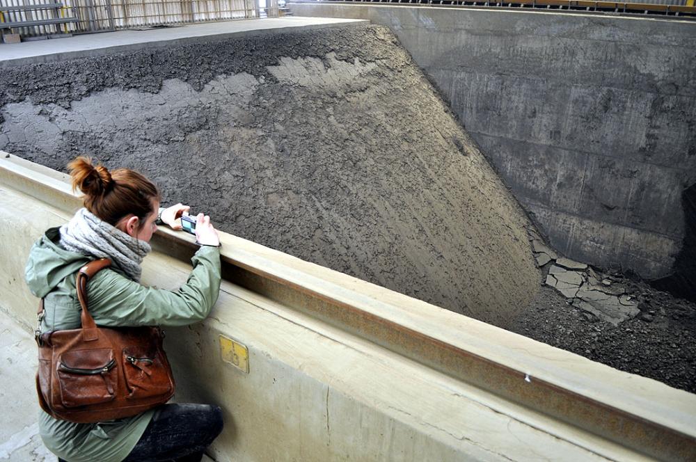Eine Frau fotografiert eine große, leere Betonwanne.