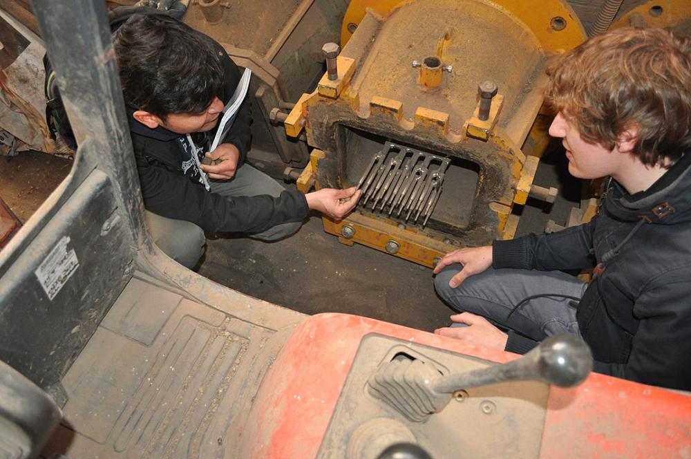 Zwei Personen untersuchen eine metallische Maschine.