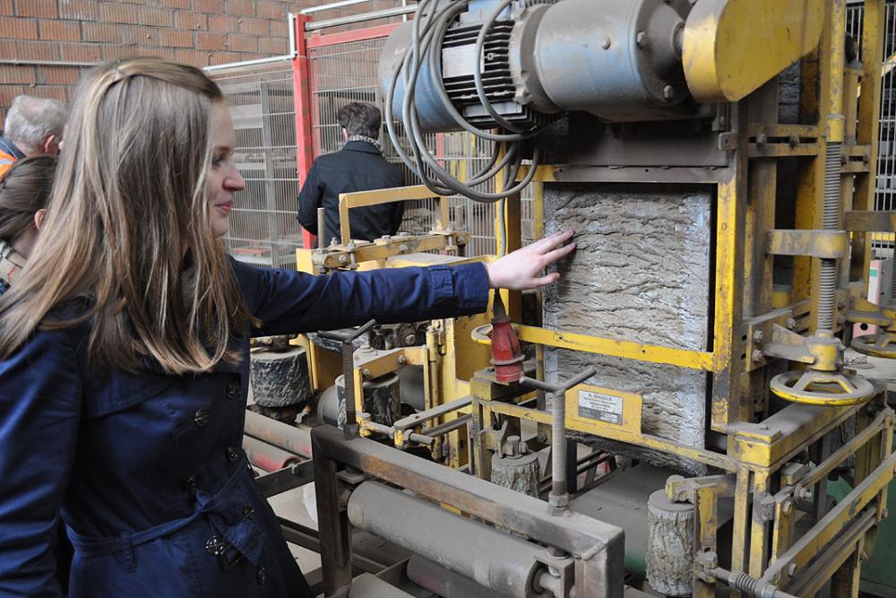 Frau berührt mit der Hand eine gelbe Industrieanlage.
