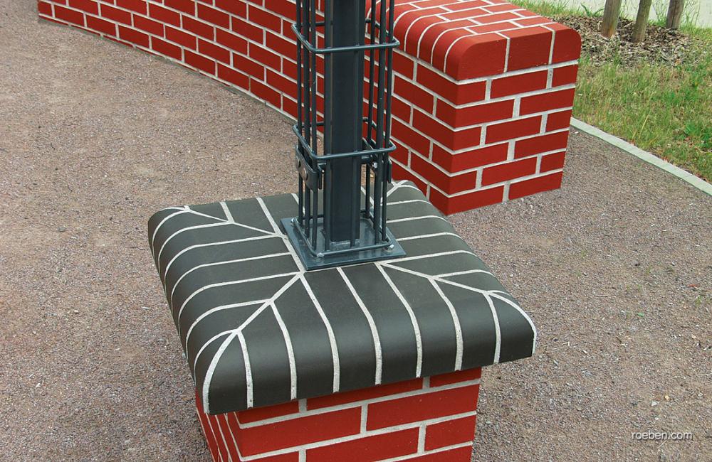 Rot-gemauerte Mauer mit schwarz-weißer Kappe, im Freien.