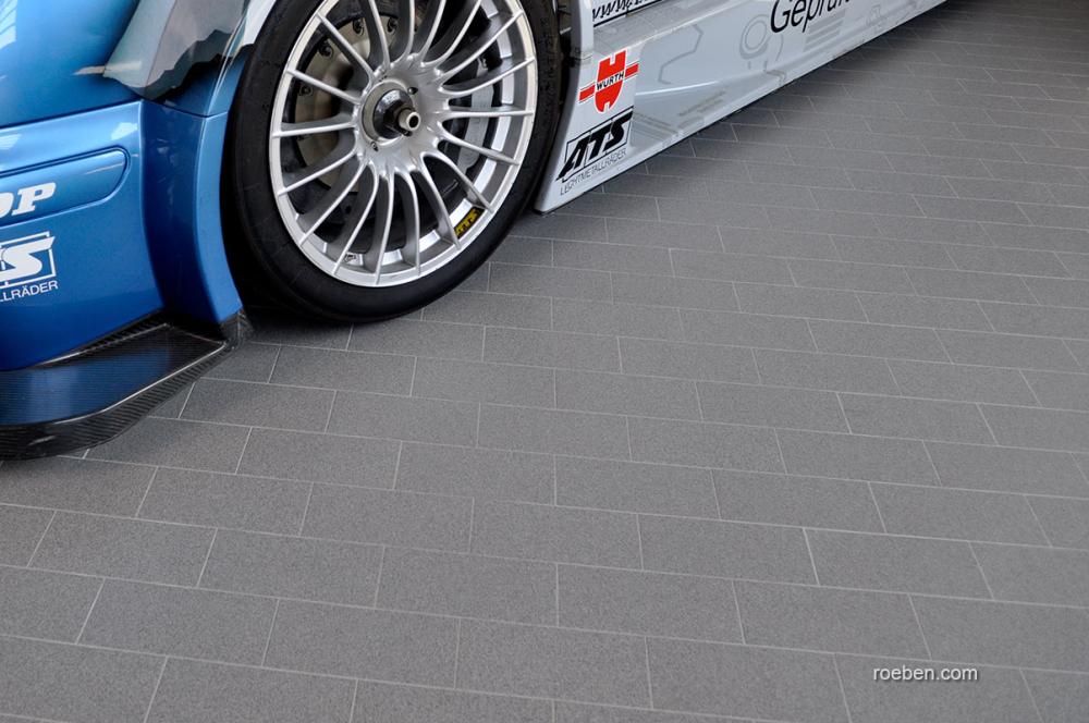 Blaues Auto mit Rennreifen auf grauem Boden.