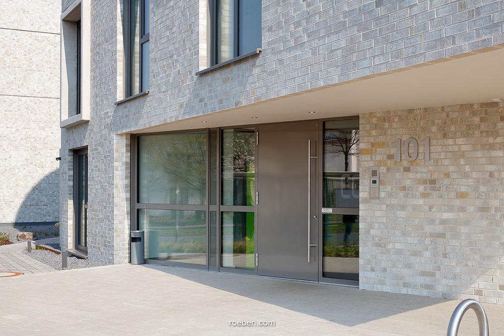 Moderne Fassade mit großem Eingangsbereich und Glasfenstern.