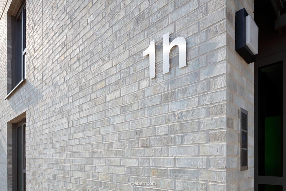 Backsteinwand mit der Aufschrift "1h" in großen Buchstaben.