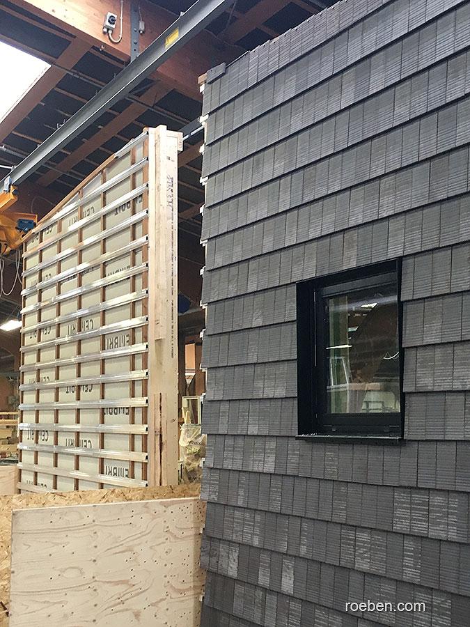 Fabrikhalle mit grauen Schindelwänden und einem kleinen Fenster.