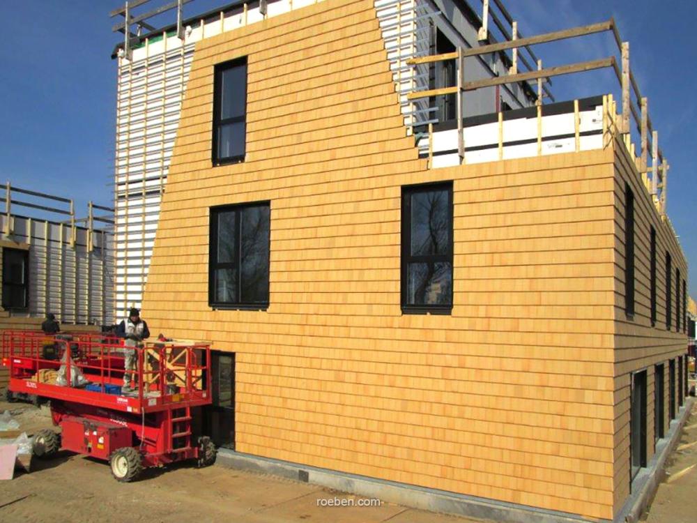 Mehrstöckiges Gebäude im Bau, gelbe Fassade, blauer Himmel, Baugerüst.