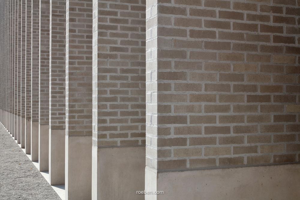 Reihe von Ziegelwänden mit schmalen Spalten in einer modernen Architekturansicht.