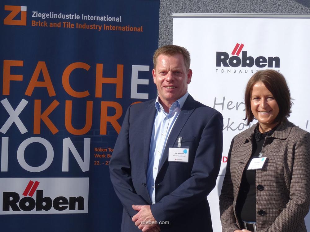 Zwei Personen vor Fachmesse-Bannern.