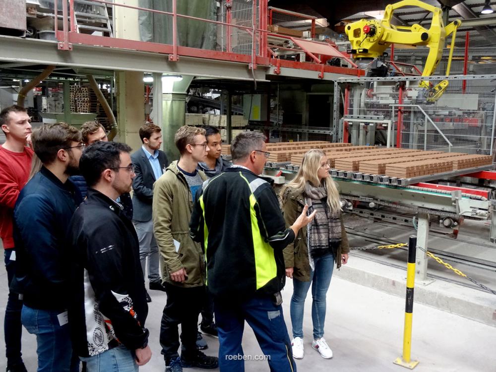 Gruppe bei einer Fabrikführung, Maschinen im Hintergrund.