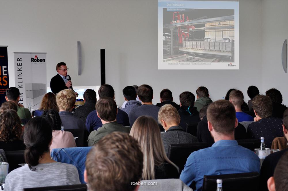 Person hält Präsentation vor Publikum in einem Konferenzraum.