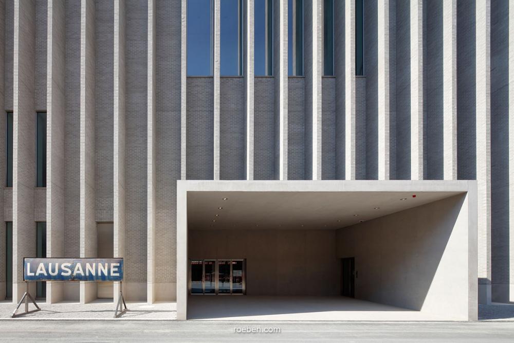Moderner Gebäudeeingang in Lausanne, graue Fassade mit vertikalen Linien.