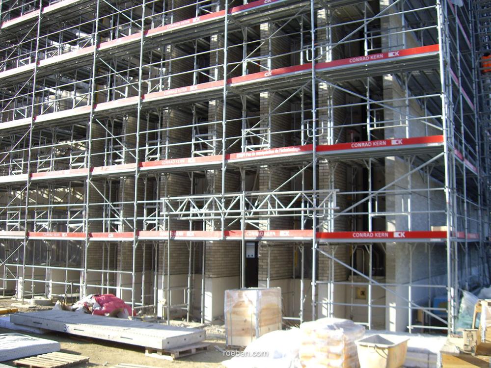 Gerüst an Baustelle mit Betonblöcken und Baustellenmaterialien.