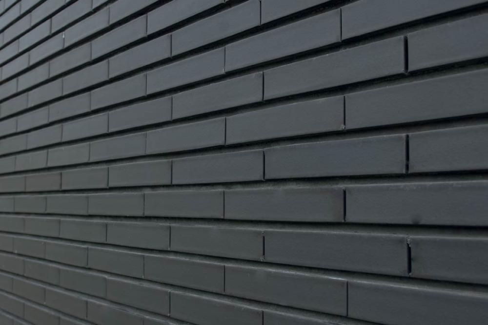 Dunkle Klinkerziegelwand mit horizontalen Linien.