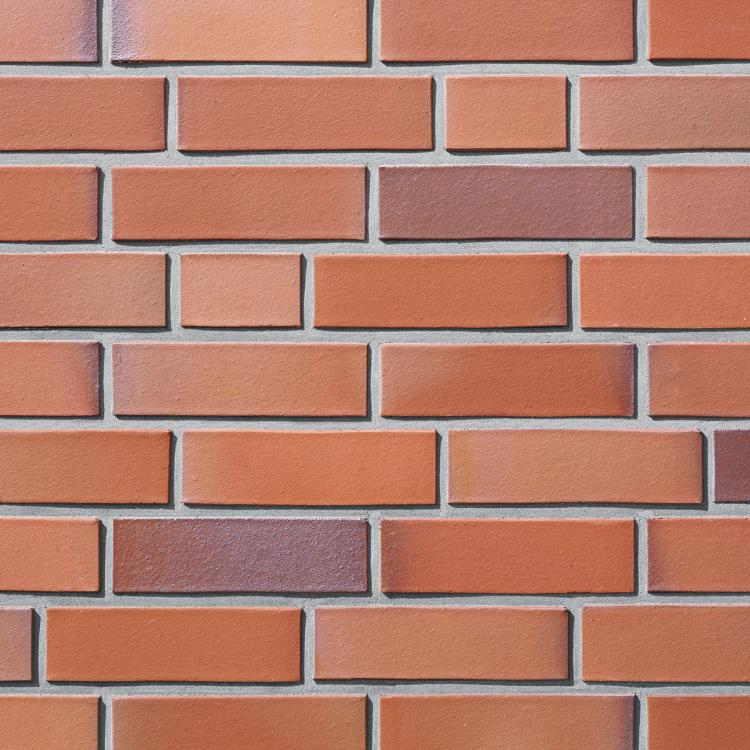 Ziegelsteinmauer mit roten und orangenen Steinen.