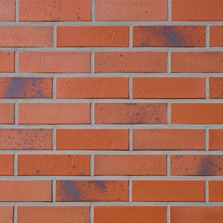 Rote Backsteinmauer mit vereinzelten dunklen Flecken.