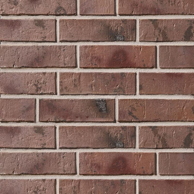 Rote Ziegelsteinmauer mit ungleichmäßigen dunklen Flecken.