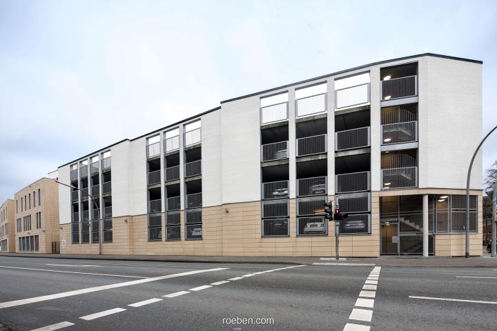 Nachhaltige Sanierung einer Putzfassade mit Keramik-Klinkern Mehrstöckiges Parkhaus an einer Kreuzung, modernes Design, bewölkter Himmel.